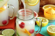 pitcher of lemonade pouring into a glass with citrus fruit